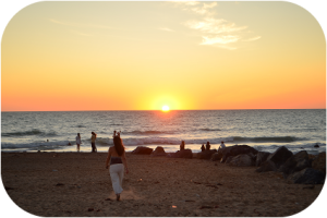 Une femme regardant le coucher de soleil sur la plage.