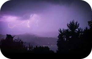 Orage avec un éclair frappant un paysage montagneux.