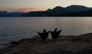 Deux personnes assises au bord d'un lac au coucher du soleil.